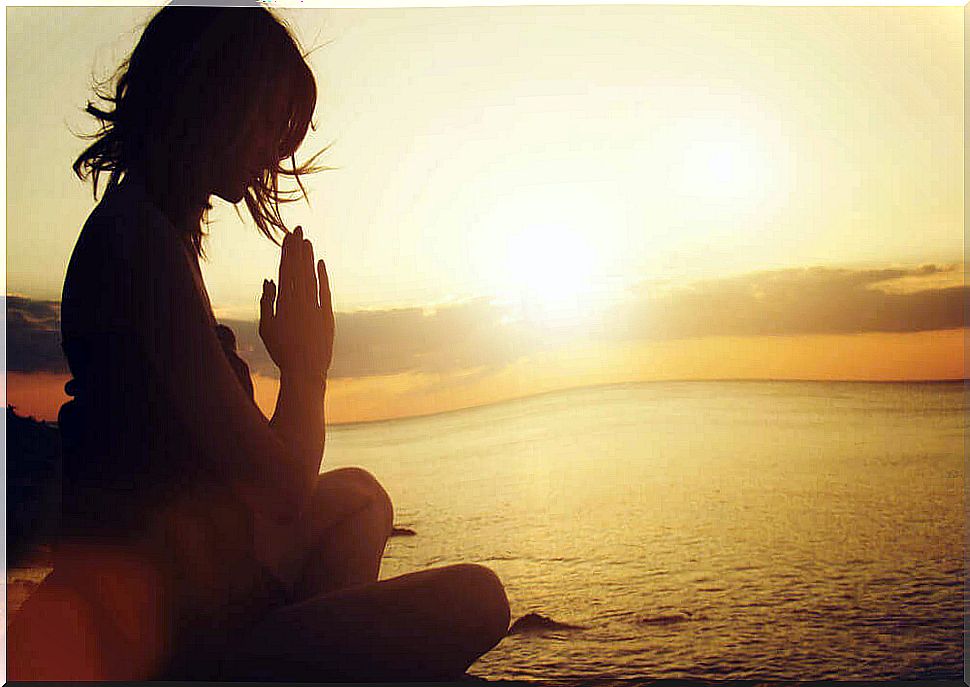 Woman meditating at sunrise.