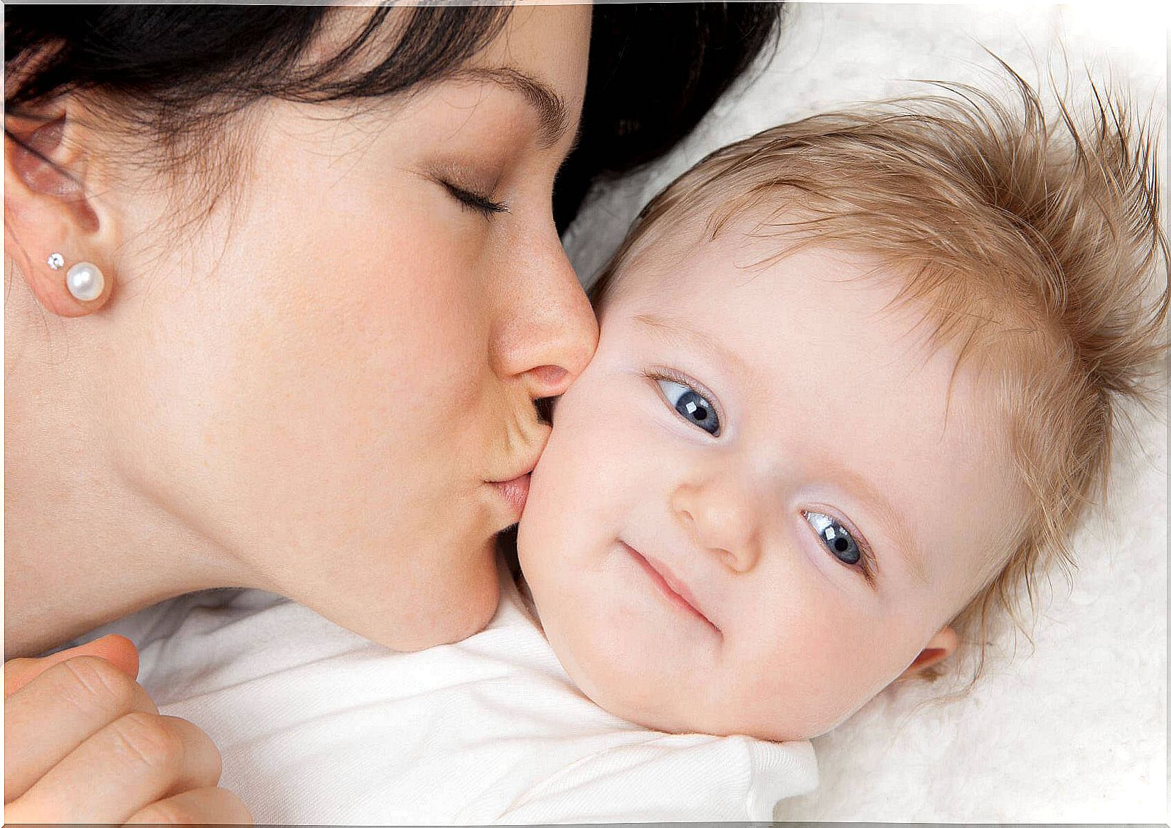 Child receiving kisses from mother