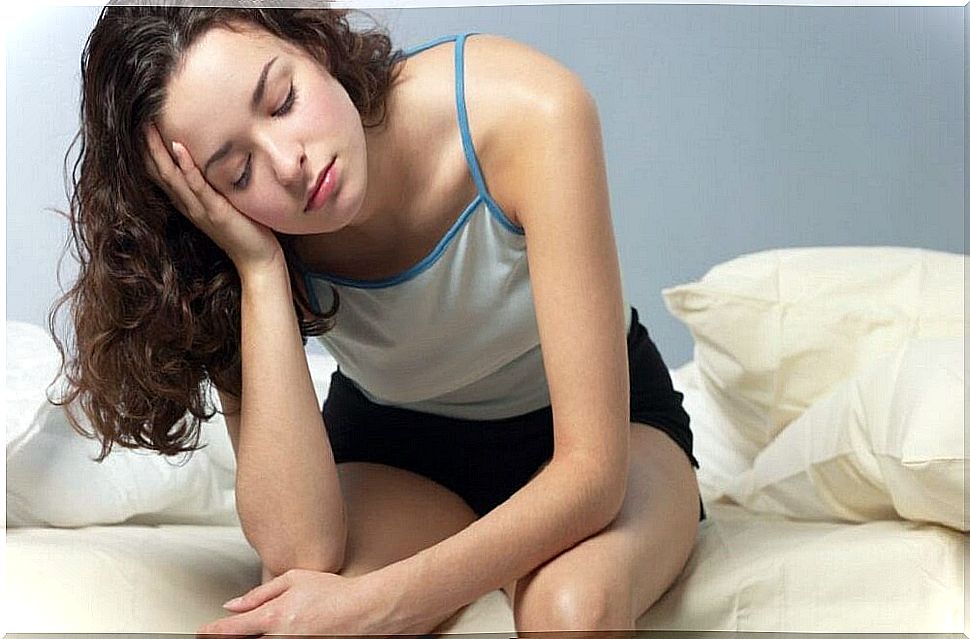 Woman sitting on bed with tired expression