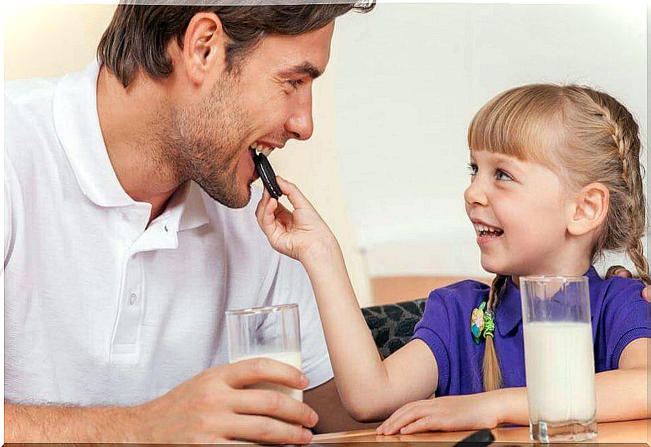 Little girl sharing a cookie with her father to learn to be generous.