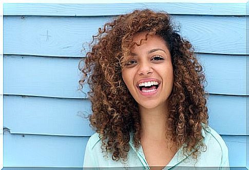 happy woman with curling hair smiling at camera